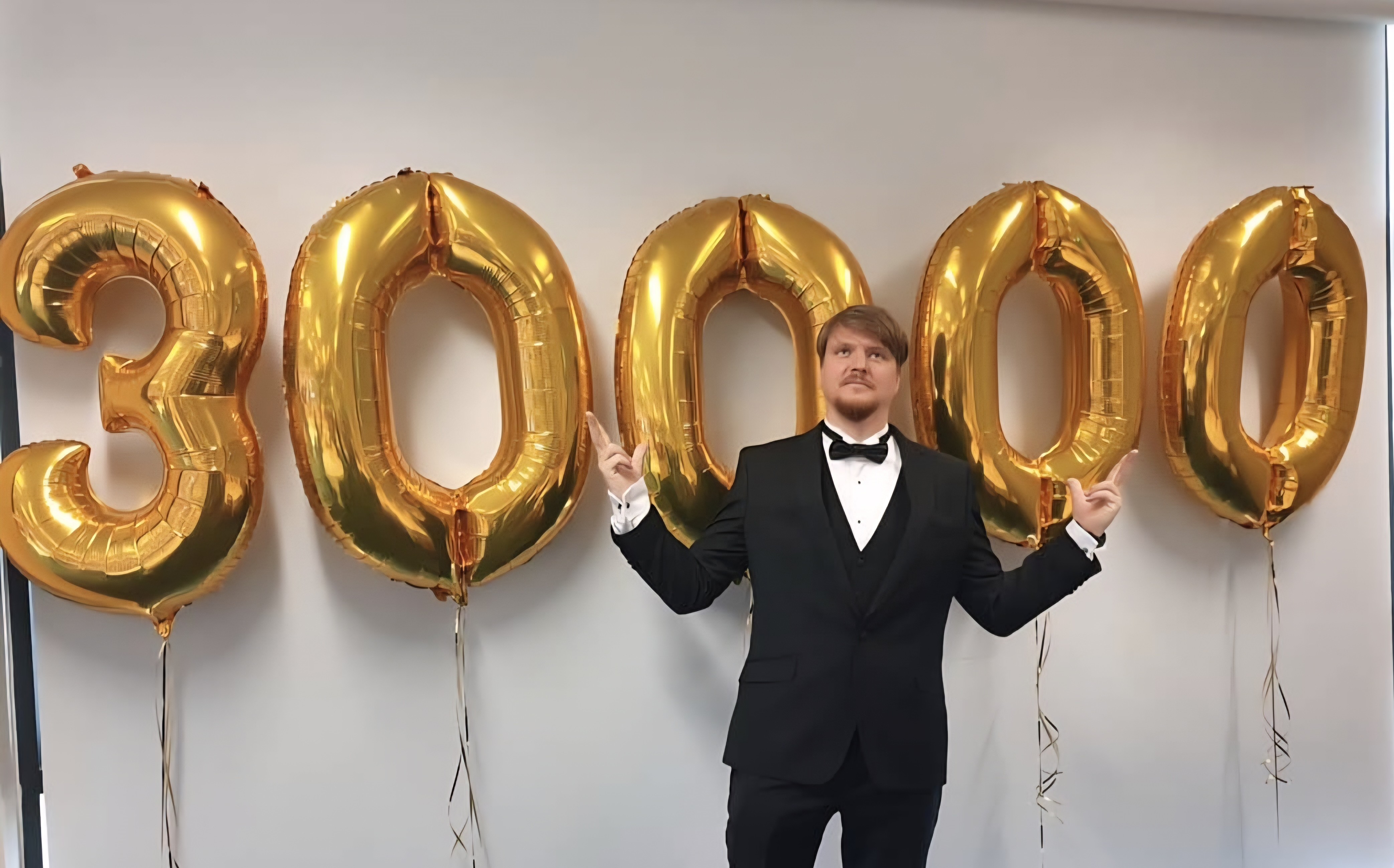 Celebrating the 30,000 members milestone in front of giant gold 30000 balloons